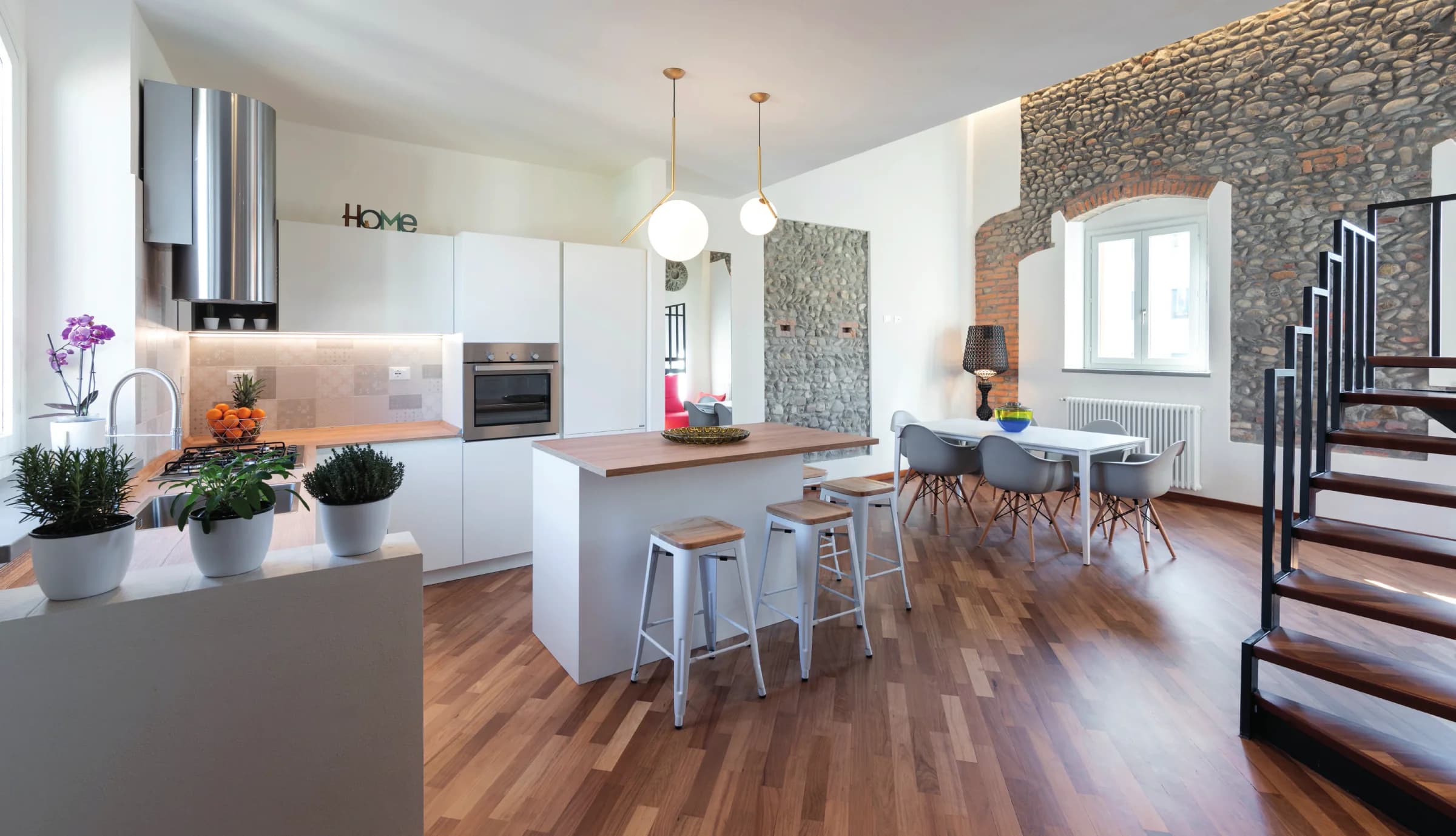 Contrasti armonici: il fascino rustico della pietra e delle travi a vista si intreccia con il rigore formale di arredi moderni, un gioco di contrappunti che valorizza la casa.