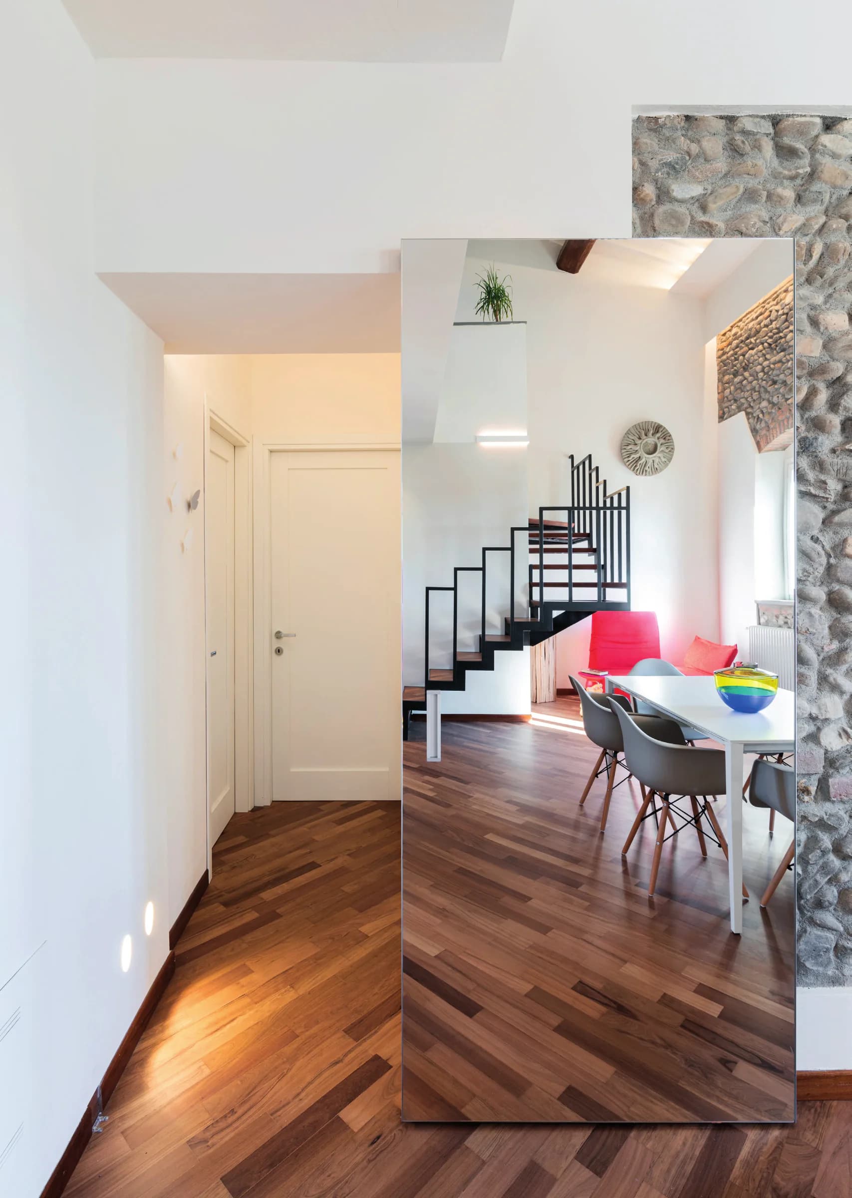 Riflette, esalta, illumina: la porta a specchio che separa la zona giorno dalla zona notte diventa protagonista - un gesto di design che rende l'ambiente più ampio, arioso e dinamico.